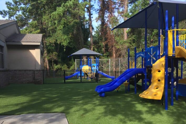 Blue and yellow slide on jungle gym with artificial playground grass