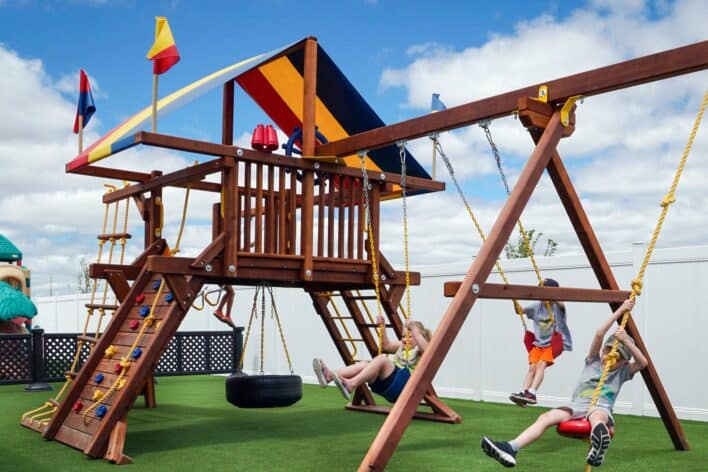 Kids swinging on jungle gym on artificial playground grass
